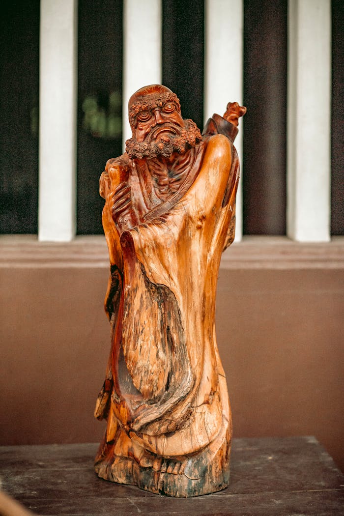 Beautifully carved wooden statue of an ancient philosopher in a serene setting.
