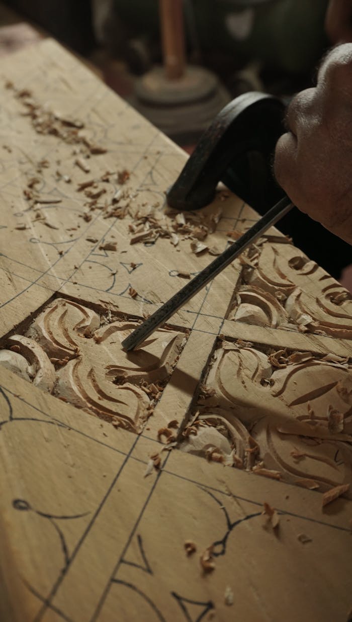 Close-up of hand carving intricate designs on wood using chisels in Bengaluru workshop.